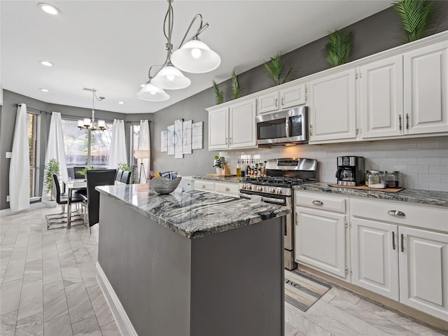 kitchen featuring appliances with stainless steel finishes, a chandelier, light marble finish floors, a kitchen island, and recessed lighting