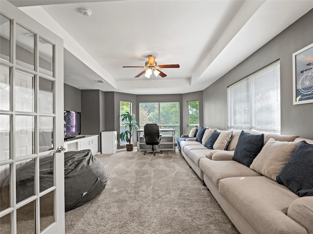 living area featuring a raised ceiling, carpet, ceiling fan, and an office area