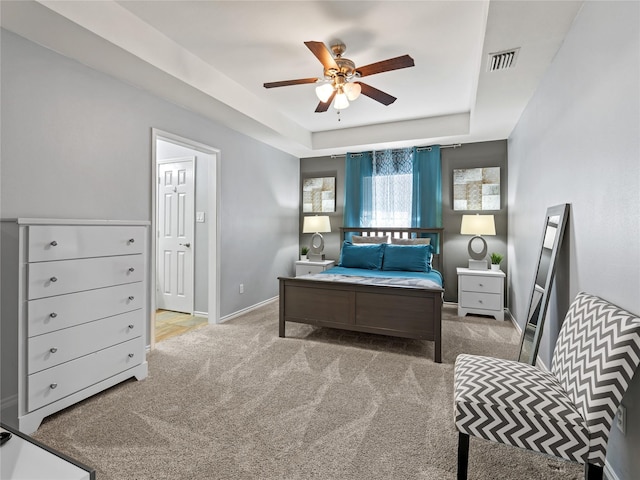 carpeted bedroom with a raised ceiling, baseboards, and ceiling fan