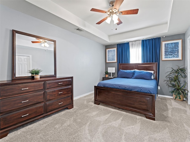 bedroom with light carpet, baseboards, a raised ceiling, and ceiling fan
