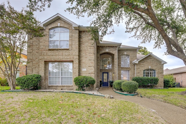 traditional-style house featuring a front lawn and brick siding