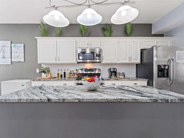 kitchen with appliances with stainless steel finishes, white cabinetry, and light stone counters