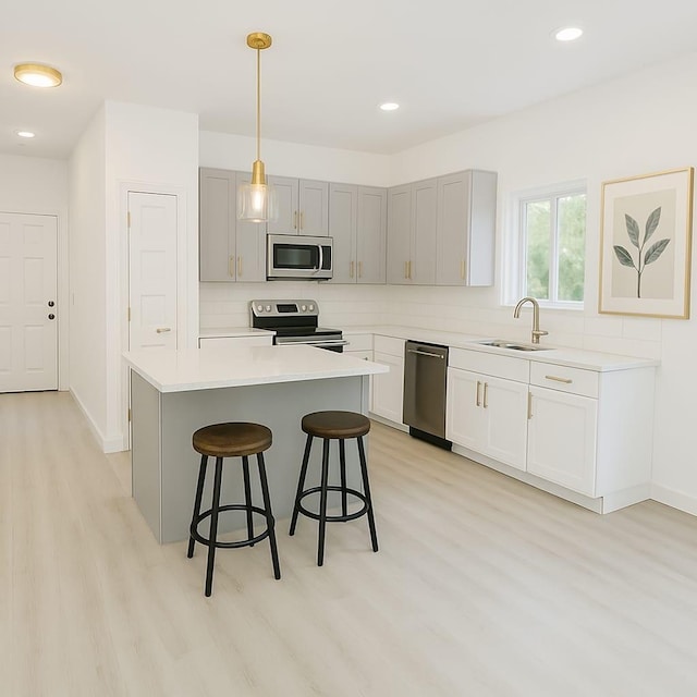 kitchen with tasteful backsplash, a sink, a breakfast bar, stainless steel appliances, and light wood-style flooring