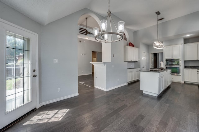 kitchen featuring a chandelier, dark countertops, high vaulted ceiling, appliances with stainless steel finishes, and white cabinetry