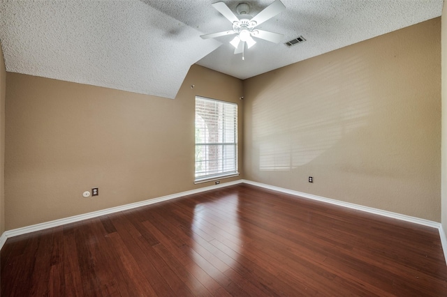 empty room featuring a ceiling fan, a textured ceiling, wood finished floors, baseboards, and lofted ceiling