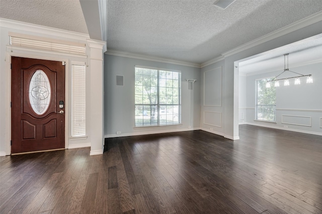 foyer entrance with dark wood finished floors, a textured ceiling, crown molding, and a chandelier