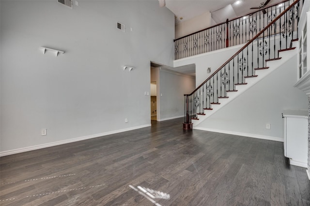 unfurnished living room featuring a high ceiling, wood finished floors, and baseboards