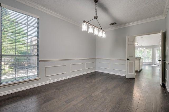 spare room featuring a chandelier, dark wood-style floors, a textured ceiling, wainscoting, and crown molding