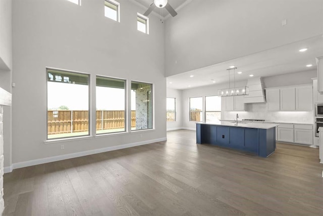 unfurnished living room with recessed lighting, wood finished floors, a healthy amount of sunlight, and ceiling fan with notable chandelier
