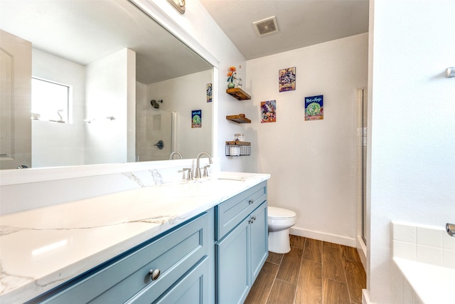 full bath featuring visible vents, wood finished floors, vanity, toilet, and tiled shower
