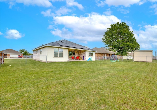back of house with a lawn, a patio, solar panels, and a fenced backyard