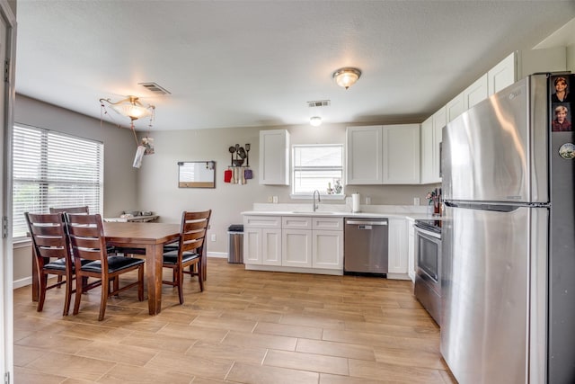 kitchen featuring visible vents, light countertops, white cabinetry, a sink, and appliances with stainless steel finishes