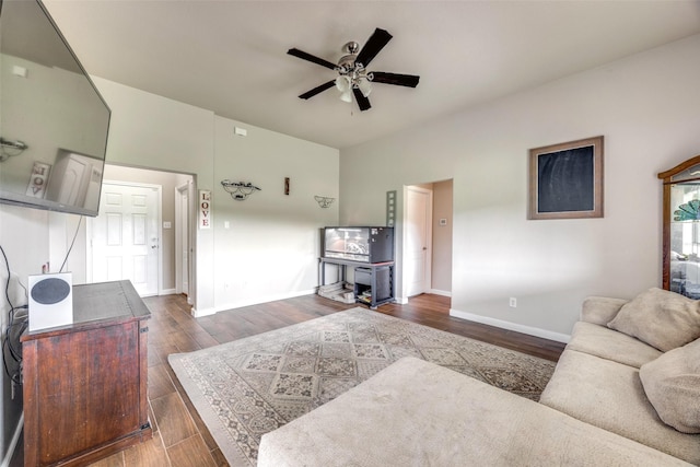 living area featuring baseboards, a ceiling fan, and dark wood-type flooring