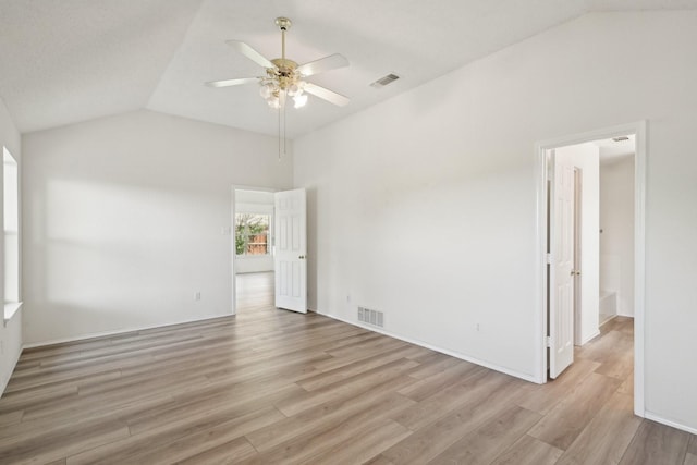 unfurnished room with ceiling fan, vaulted ceiling, visible vents, and light wood-style flooring