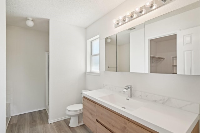 full bath with walk in shower, wood finished floors, toilet, and vanity