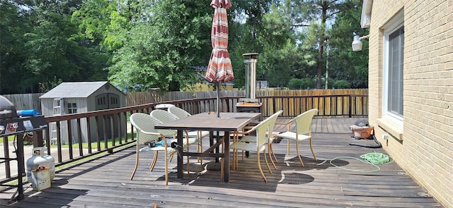 deck featuring an outdoor structure, a fenced backyard, a shed, and outdoor dining space