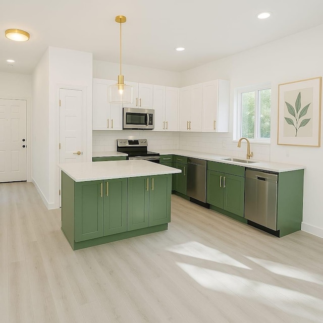 kitchen with white cabinets, light wood-style flooring, a sink, green cabinets, and appliances with stainless steel finishes