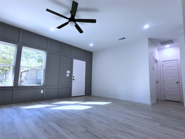unfurnished living room featuring recessed lighting, a decorative wall, and visible vents
