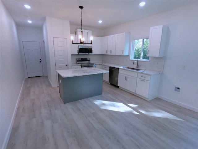 kitchen featuring white cabinets, light wood finished floors, stainless steel appliances, a sink, and a center island