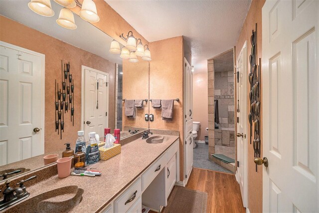 5625 Guadalajara Dr, North Richland Hills, TX 76180 - bathroom featuring double vanity, toilet, wood finished floors, and tiled shower