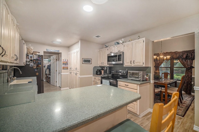 5625 Guadalajara Dr, North Richland Hills, TX 76180 - kitchen featuring stainless steel appliances, a sink, a chandelier, light wood finished floors, and a peninsula