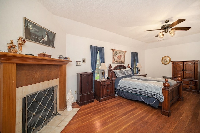 5625 Guadalajara Dr, North Richland Hills, TX 76180 - bedroom with wood finished floors, a tiled fireplace, and a ceiling fan