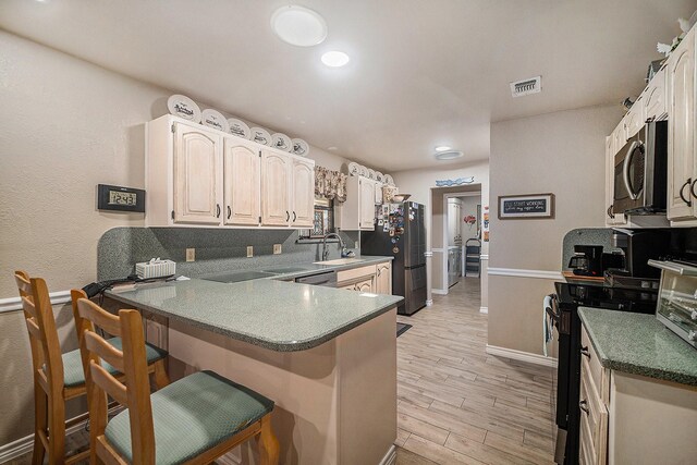 5625 Guadalajara Dr, North Richland Hills, TX 76180 - kitchen with stainless steel appliances, a breakfast bar area, a peninsula, a sink, and light wood-type flooring