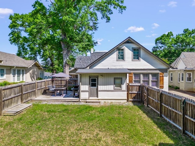 rear view of property featuring board and batten siding, a fenced backyard, a yard, and a deck