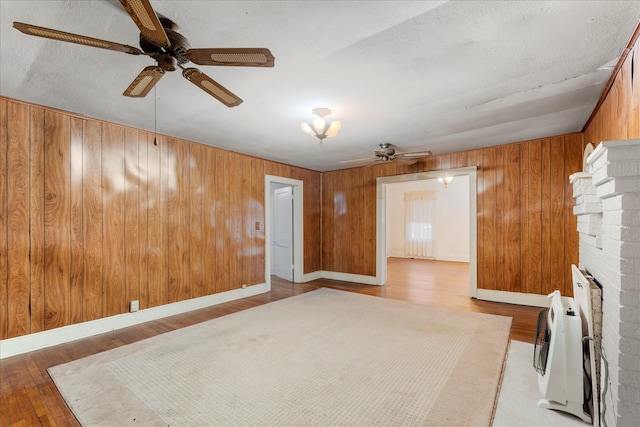 1302 E 1st St, Mount Pleasant, TX 75455 - spare room featuring wood walls, heating unit, wood finished floors, and ceiling fan