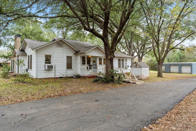 1302 E 1st St, Mount Pleasant, TX 75455 - view of front of home with a chimney, a shingled roof, cooling unit, an outdoor structure, and a porch