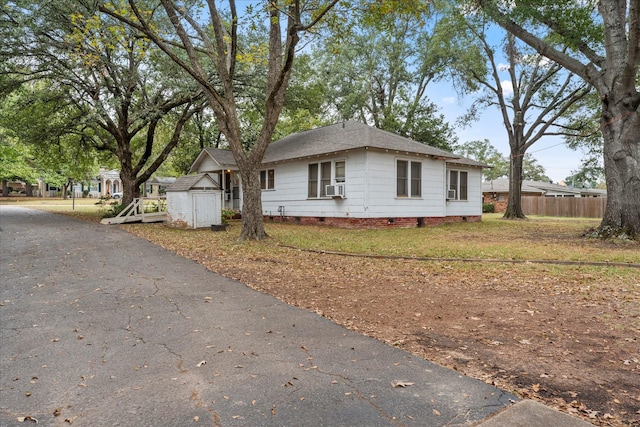 1302 E 1st St, Mount Pleasant, TX 75455 - view of home's exterior featuring crawl space, fence, a shingled roof, an outdoor structure, and a shed