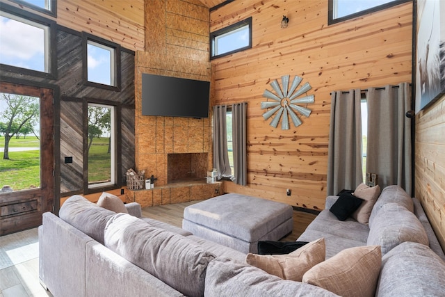 living room featuring a fireplace, wood finished floors, a high ceiling, and wood walls