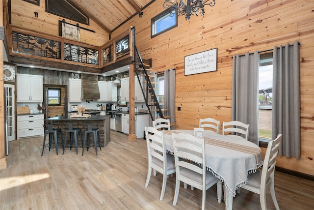 dining space with wood walls, high vaulted ceiling, and a healthy amount of sunlight