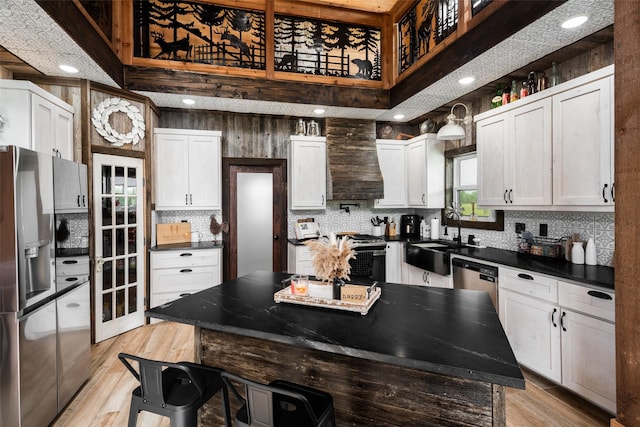 kitchen with a sink, light wood-type flooring, stainless steel appliances, premium range hood, and backsplash