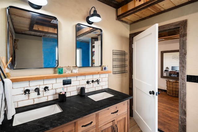 bathroom featuring backsplash, double vanity, wood finished floors, and a sink