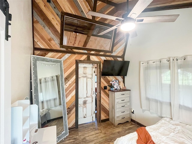 bedroom with beamed ceiling, wooden walls, and wood finished floors