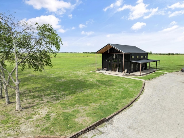 view of yard featuring driveway, an outbuilding, a rural view, and a pole building