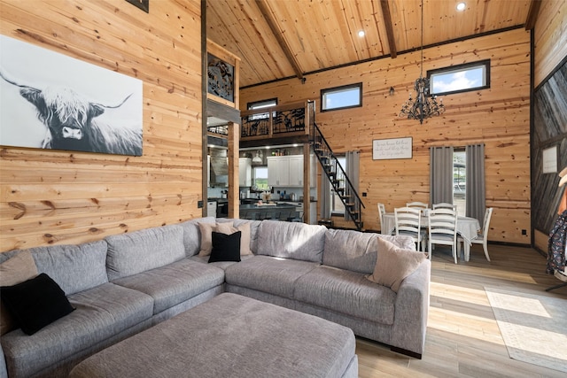 living room featuring stairs, light wood-style floors, wooden walls, wood ceiling, and a high ceiling