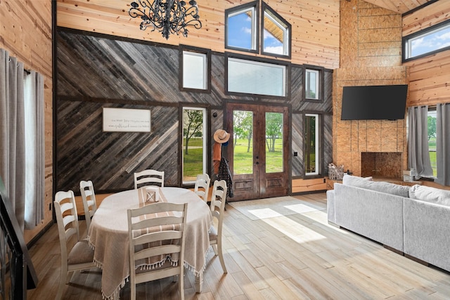 interior space with a high ceiling, wooden walls, wood finished floors, and an inviting chandelier