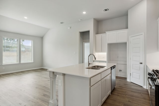 kitchen with stainless steel appliances, wood finished floors, visible vents, a sink, and a center island with sink