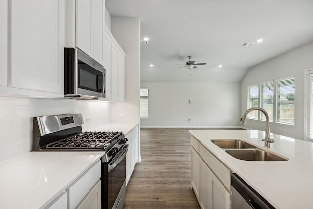 kitchen featuring lofted ceiling, dark wood-style floors, stainless steel appliances, a sink, and tasteful backsplash