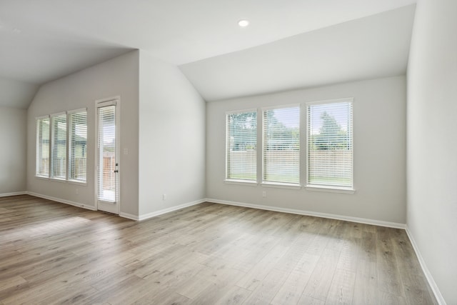 unfurnished living room featuring lofted ceiling, baseboards, and light wood finished floors