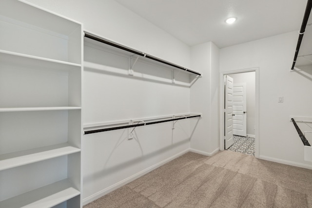 walk in closet featuring light colored carpet