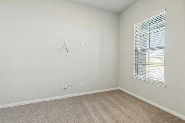 spare room with light colored carpet, baseboards, and plenty of natural light