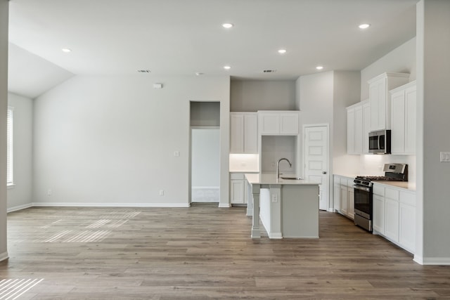 kitchen featuring a sink, light wood-type flooring, a center island with sink, appliances with stainless steel finishes, and open floor plan