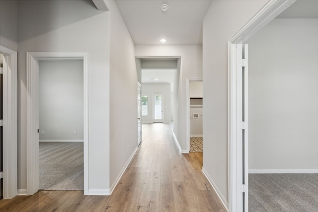 hallway with light wood finished floors, baseboards, and recessed lighting