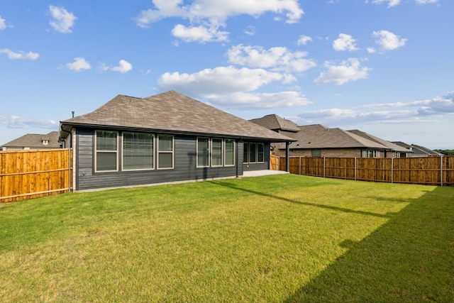 rear view of property featuring a fenced backyard, a yard, a patio, and a shingled roof