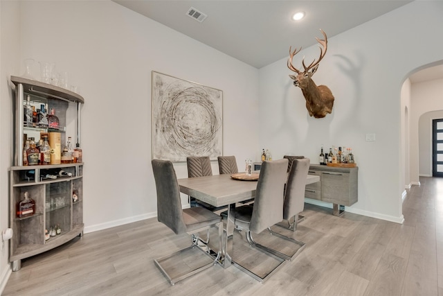 dining room with visible vents, baseboards, wood finished floors, and arched walkways