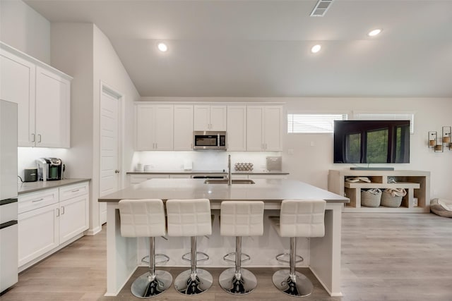 kitchen featuring light wood-type flooring, visible vents, a sink, and stainless steel microwave