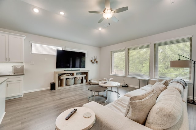 living room featuring visible vents, light wood finished floors, baseboards, and ceiling fan
